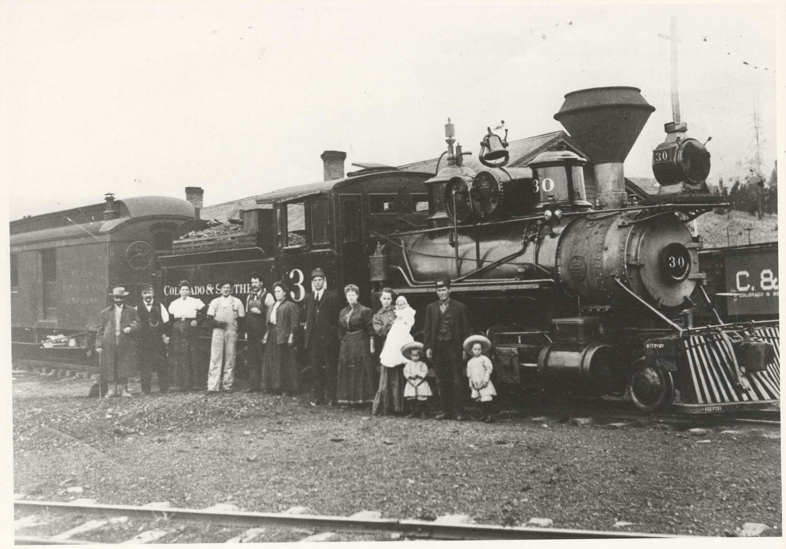 Colorado and Southern trains served Nathrop and the Western Slope via the Alpine Tunnel after the demise of the storied Denver, South Park and Pacific about 1899. The C & S struggled financially as did its predecessor, finally abandoning the run to Gunnison in 1910 with closure of the Tunnel. The line from Buena Vista to Hancock was abandoned in 1924.  (1) Maud Perschbacher dates this picture as taken in July or August, 1910 at the Alma Station. She identified the people from left to right as: a blind man named Redman, depot agent John Geyer and his wife, fireman Bill Cantonwine, engineer Bill Gallagher and his wife, conductor Jack Harris and his wife, Maud (Matthews) Pershcbacher holding her son, William Earnest Perschbacher (aged 3 months), John Raymond Perschbacher (son of Joseph and Maud), brakeman Joseph T. Perschbacher and Leonard Perschbacher (son of Joseph and Maud).  (4)