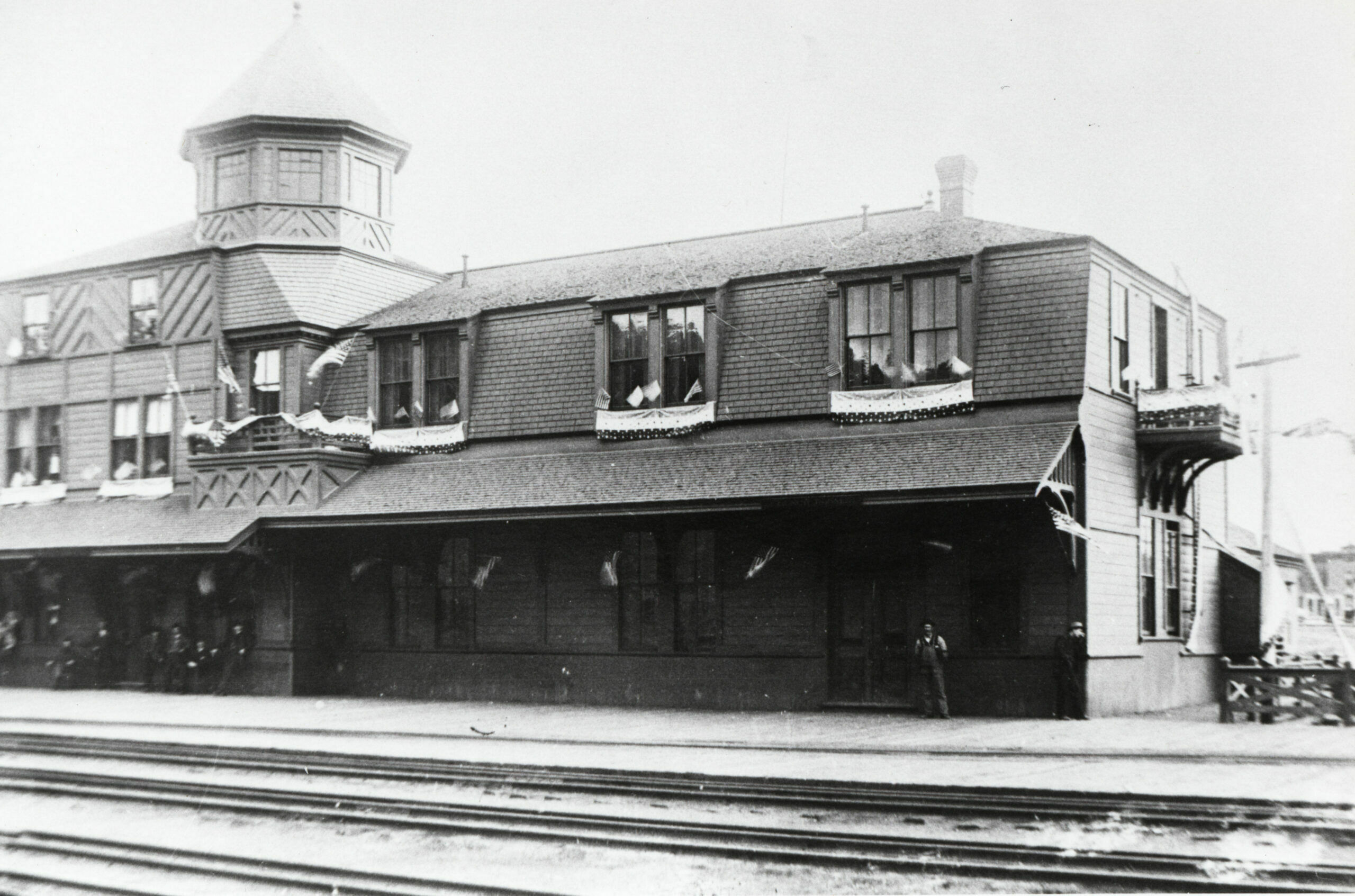 The Hotel Monte Christo was decorated with American flags and bunting in commemoration of the Fourth of July. The lunchroom occupied this wing of the hotel, and the main entrance was to the left, where some gentlemen were relaxed under the canopy. By 1890, standard-gauge rail had reached Salida, and dual-gauge track was clearly visible here.  (2)